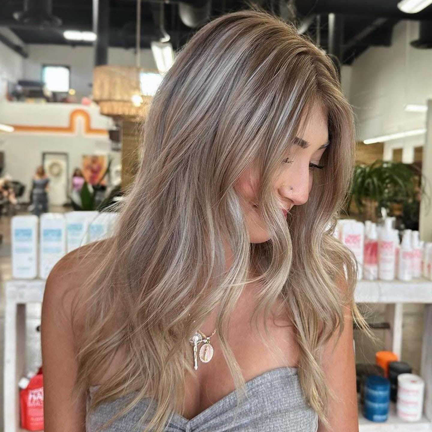 Woman with long, wavy blonde hair in a salon, showcases fresh hairstyle.